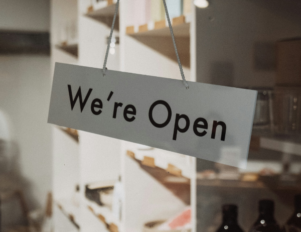 A photo of a sign that reads "We're Open" from Unsplash user Samuel Regan-Asante